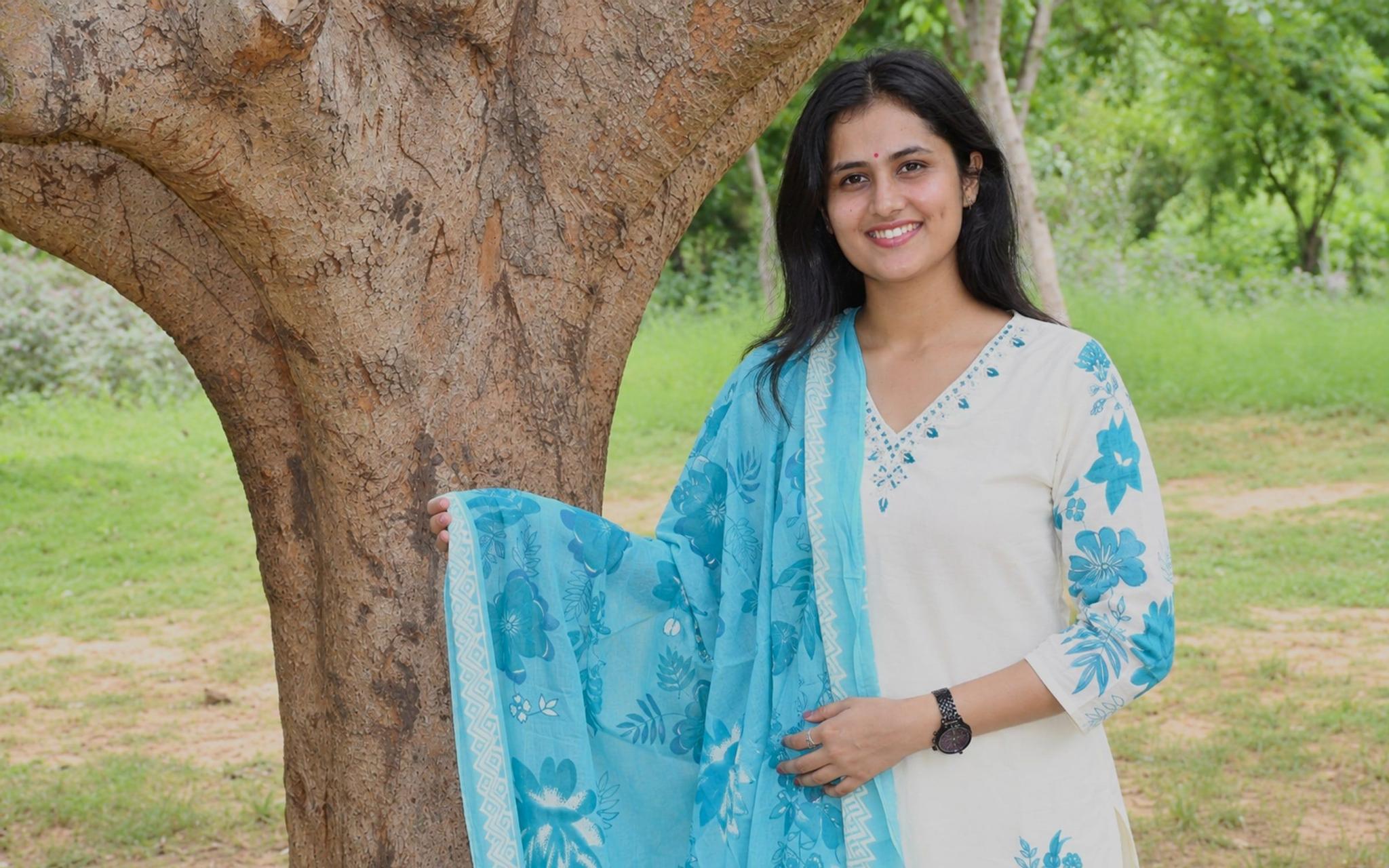 Model wearing the ivory and blue floral suit set beneath a tree