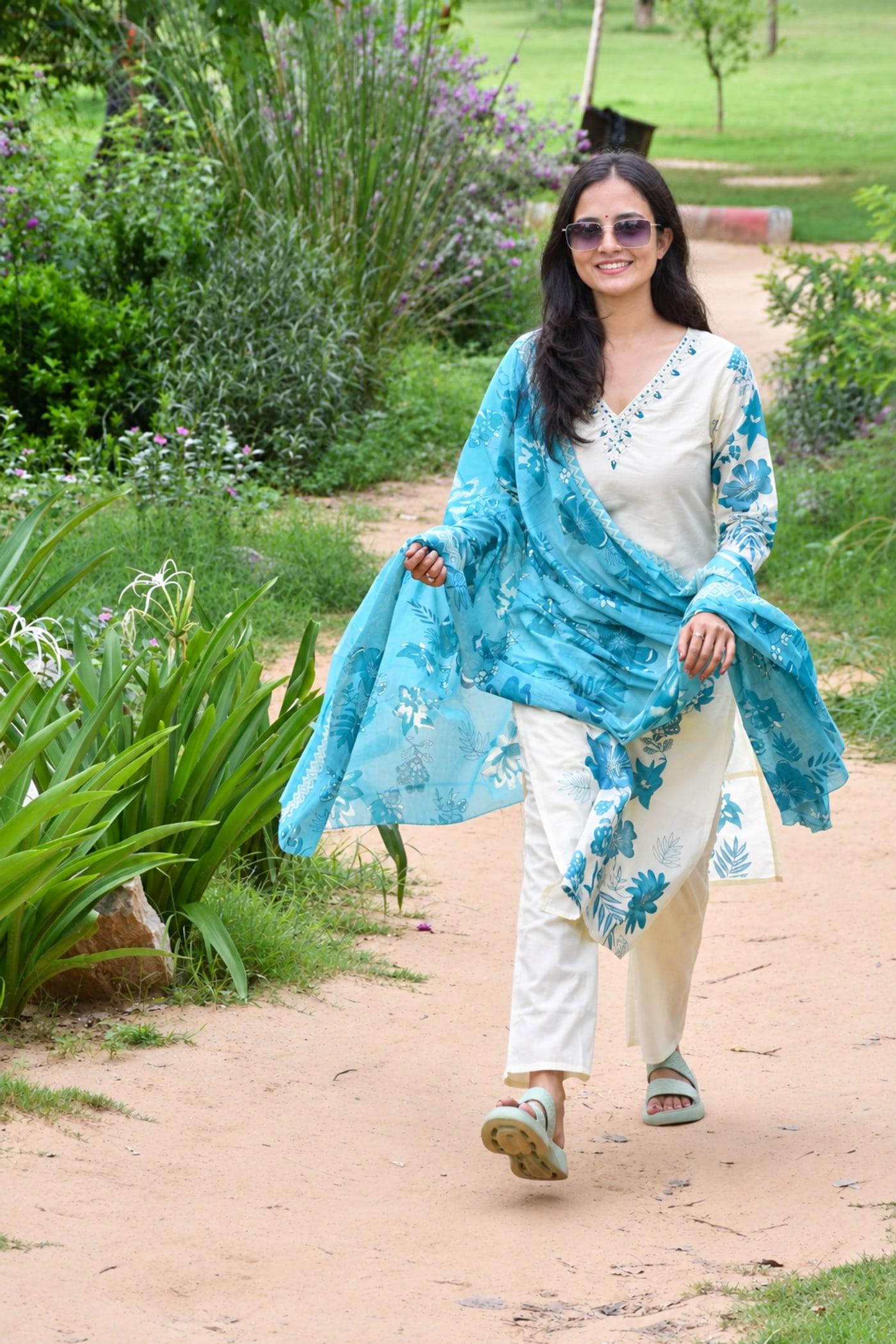 Ivory & Blue suit set worn walking on a garden path, teal dupatta caught mid-air