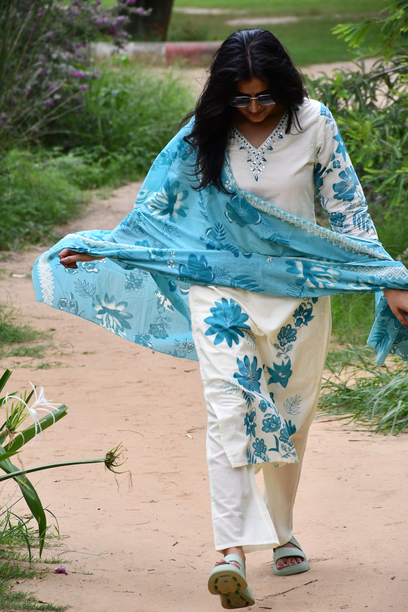 Ivory suit set worn walking, teal dupatta caught mid-air