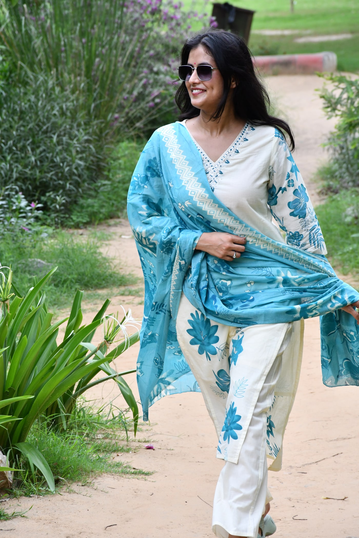 Ivory suit set worn walking, teal dupatta trailing