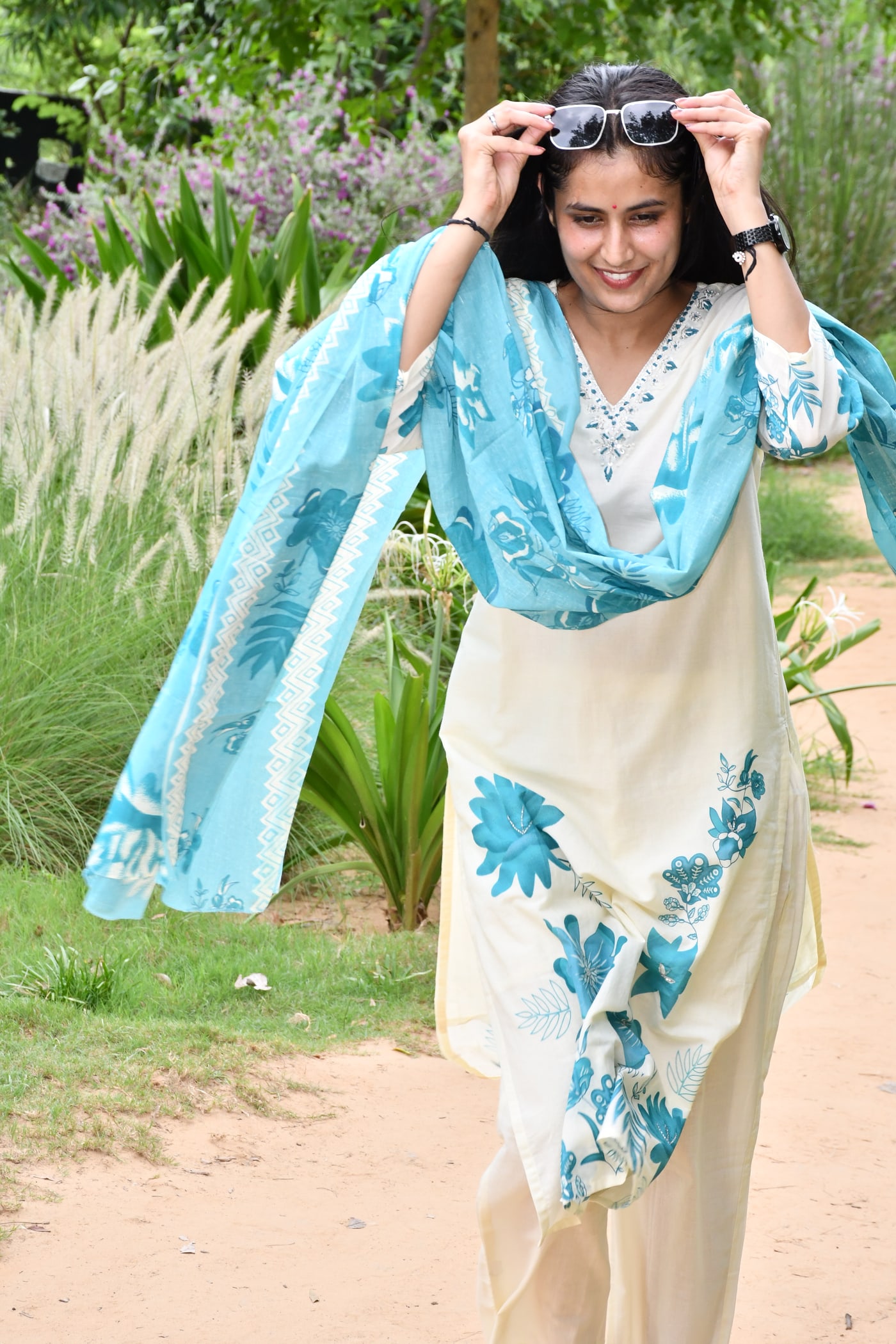 Ivory kurta with the teal dupatta lifted overhead